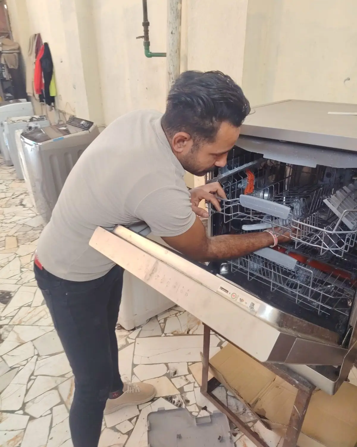 فني من شركة إي جي يفحص أرفف غسالة أطباق وبابها مفتوح.